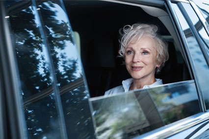 Beautiful elderly woman riding in the backseat of a car.
