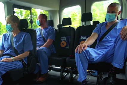 People in masks and scrubs on a Shuttle.