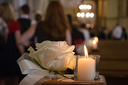 White rose and burning candle in a church