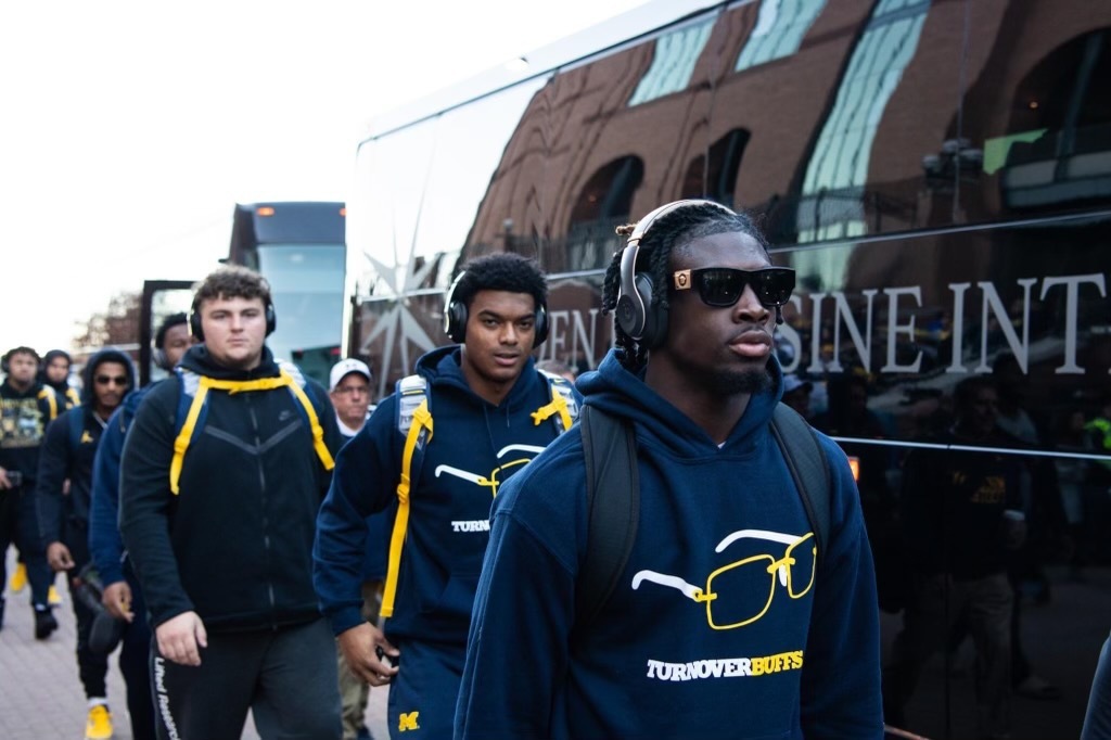 Image of UofM football team beside a GLI Charter Bus