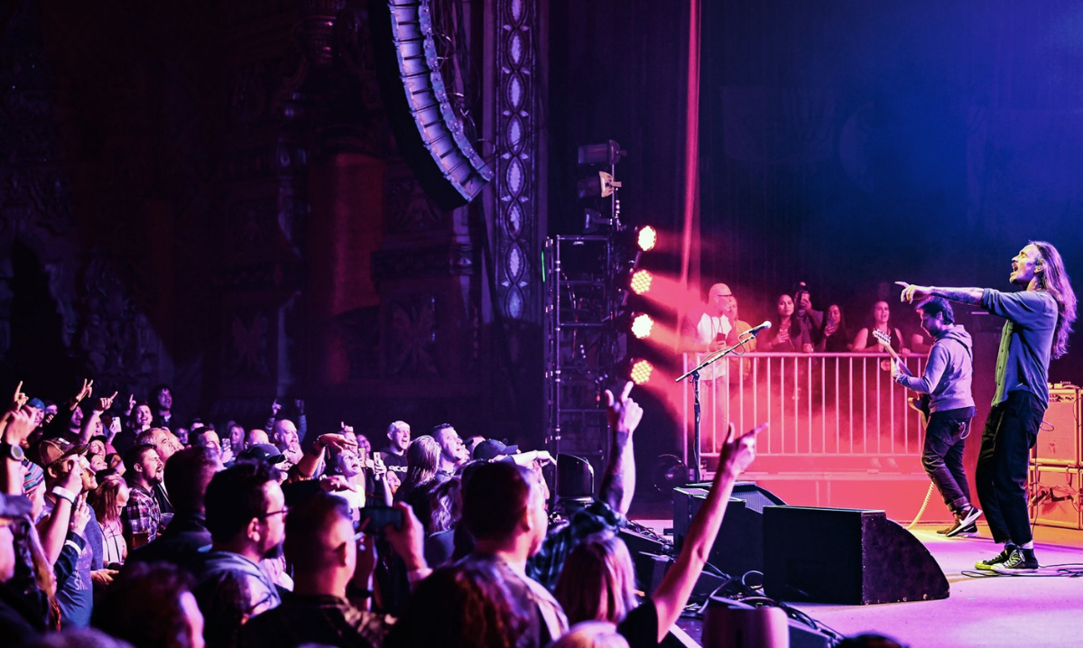 Excited concert crowd cheering and watching performers on-stage.