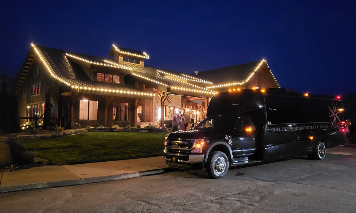 Golden Limo Executive Coach parked outside a venue destination at night waiting for riders to board.