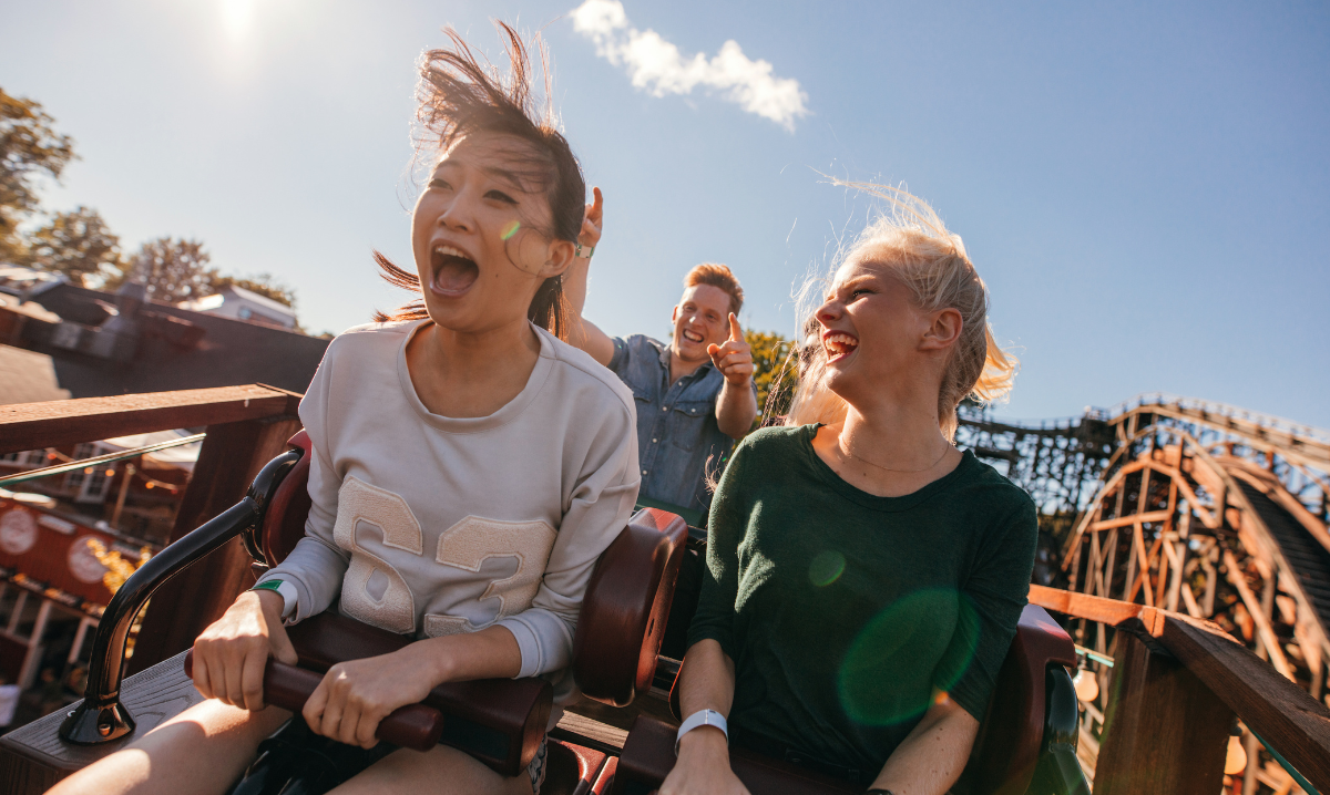 Excited roller coaster riders experiencing the trill of the ride and summer!