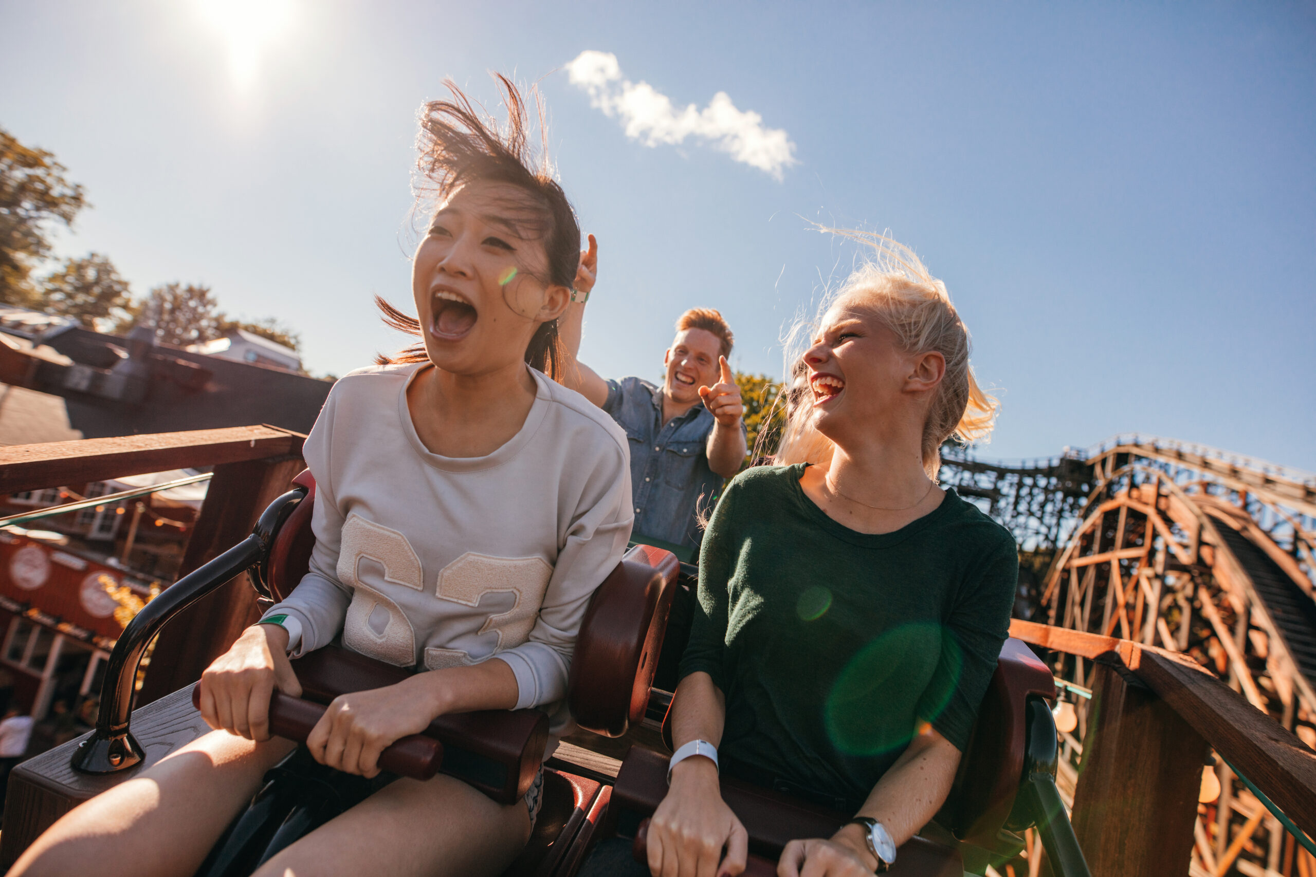 Excited roller coaster riders experiencing the trill of the ride and summer!