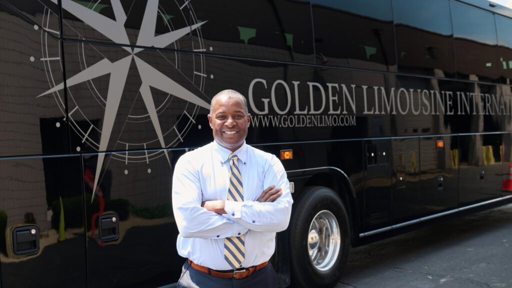 Golden Limousine International President & CEO Sean Duval standing with Golden Limousine Charter Bus in celebration of Golden's 33rd Business Anniversary!