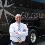 Golden Limousine International President & CEO Sean Duval standing with Golden Limousine Charter Bus in celebration of Golden's 33rd Business Anniversary!