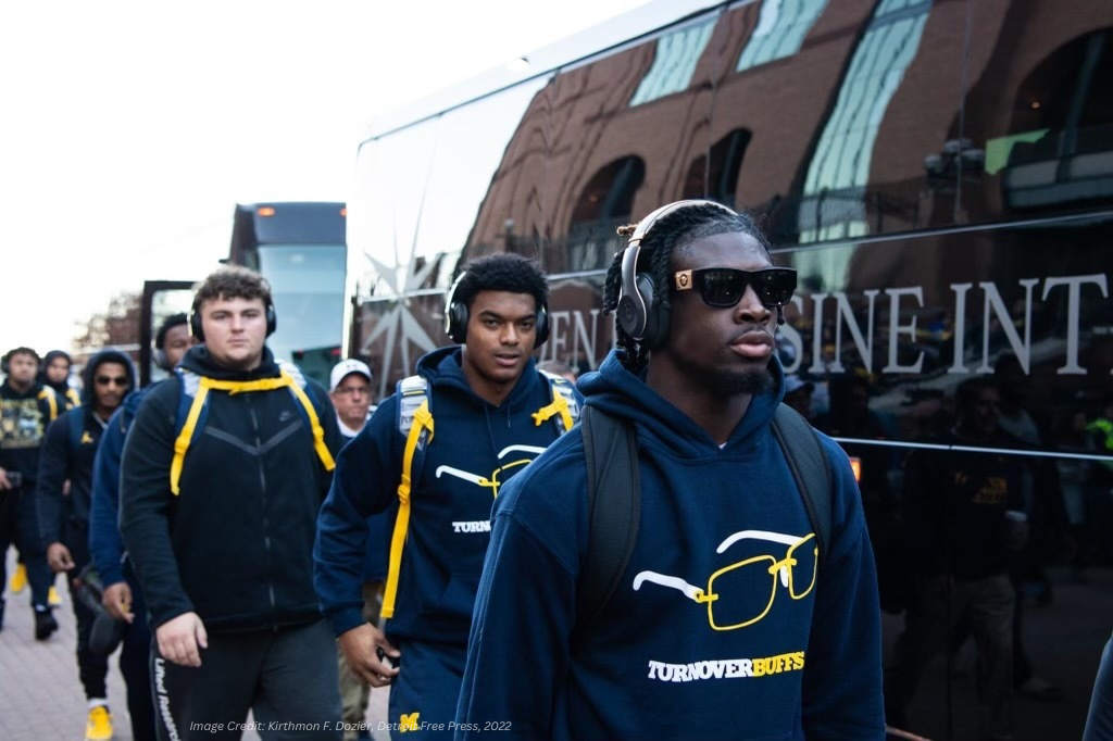 Image of UofM football team beside a GLI Charter Bus