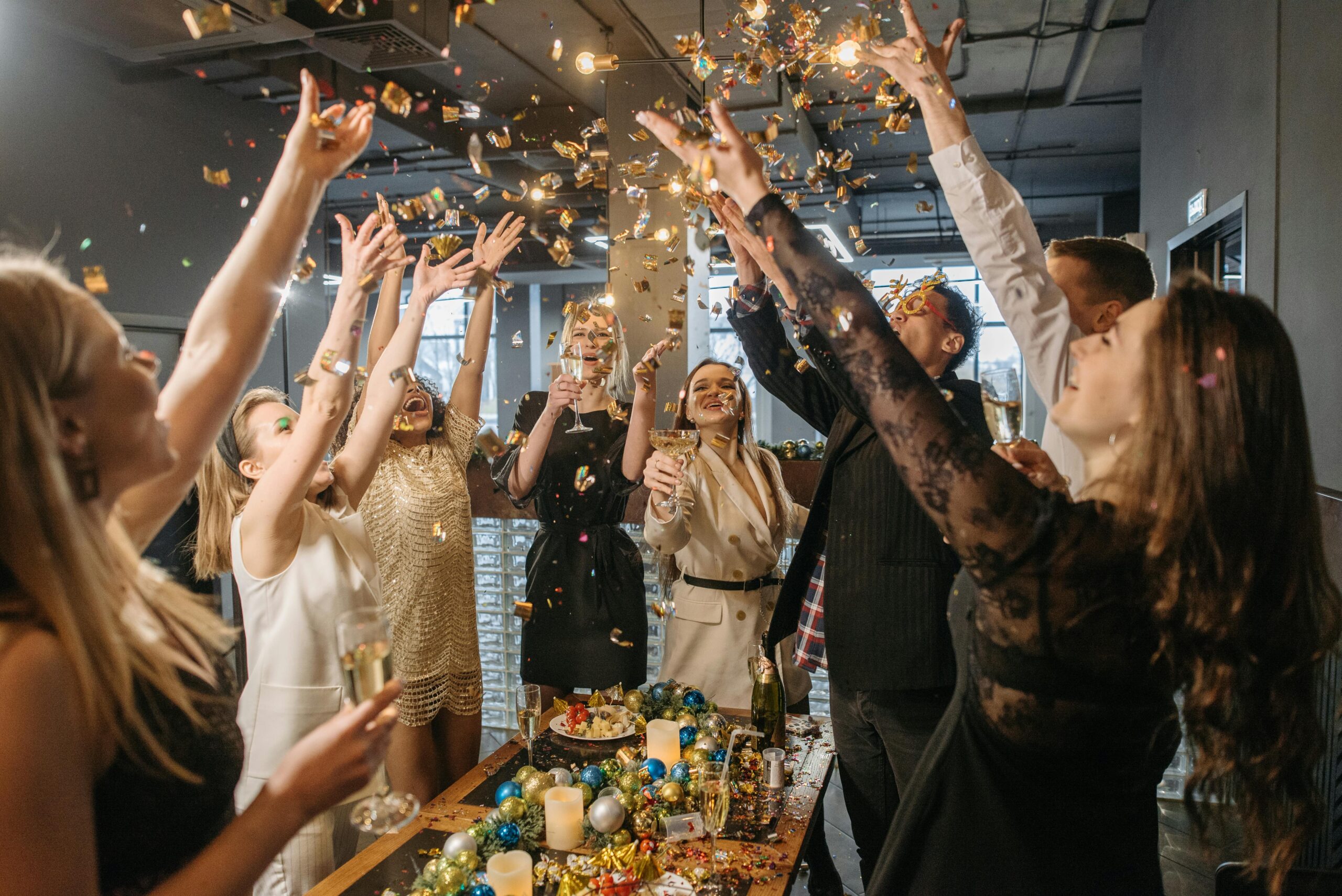 Corporate employees throwing confetti in the air at a holiday work party.