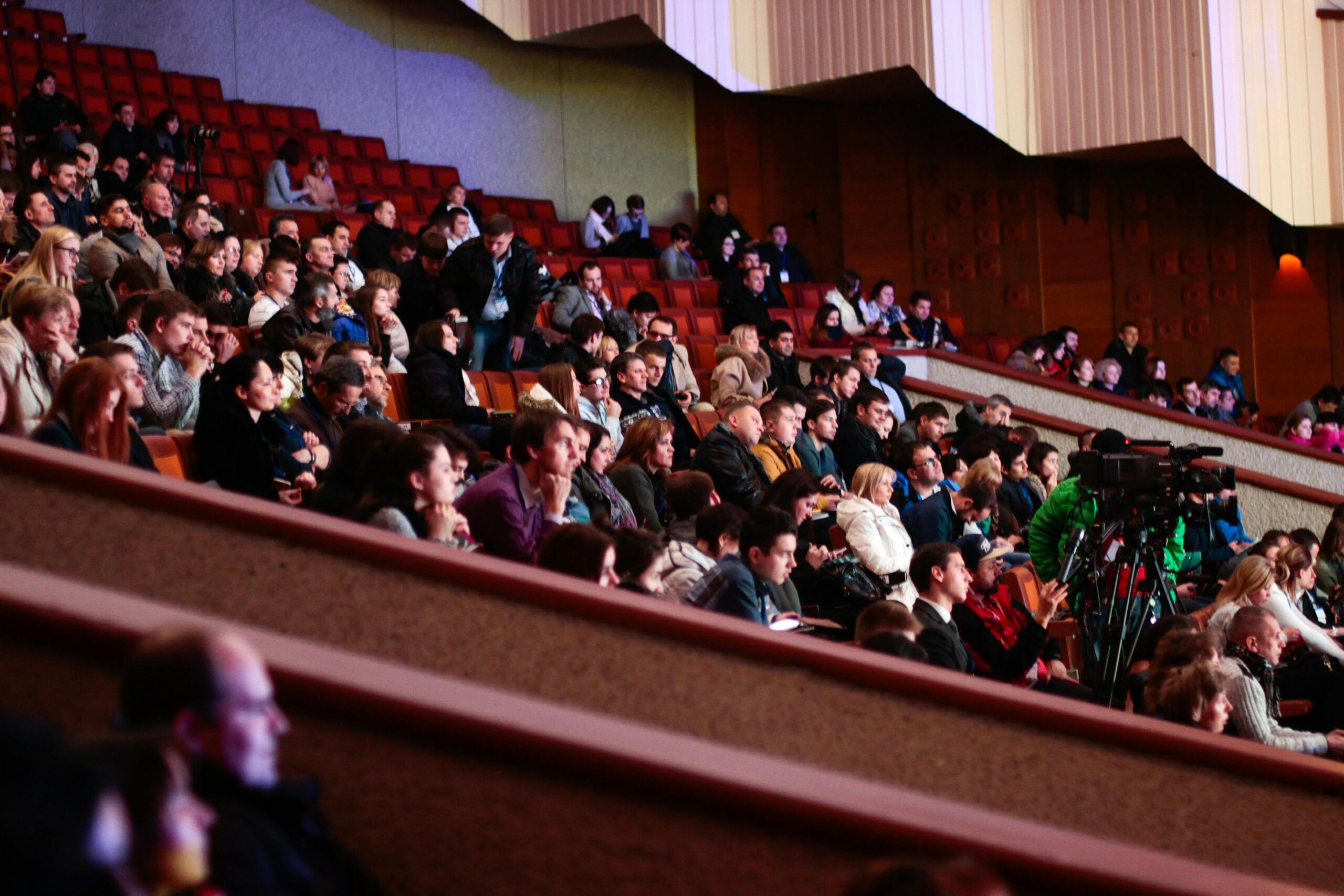 Crowd of people sitting in a theater listening to a conference event.