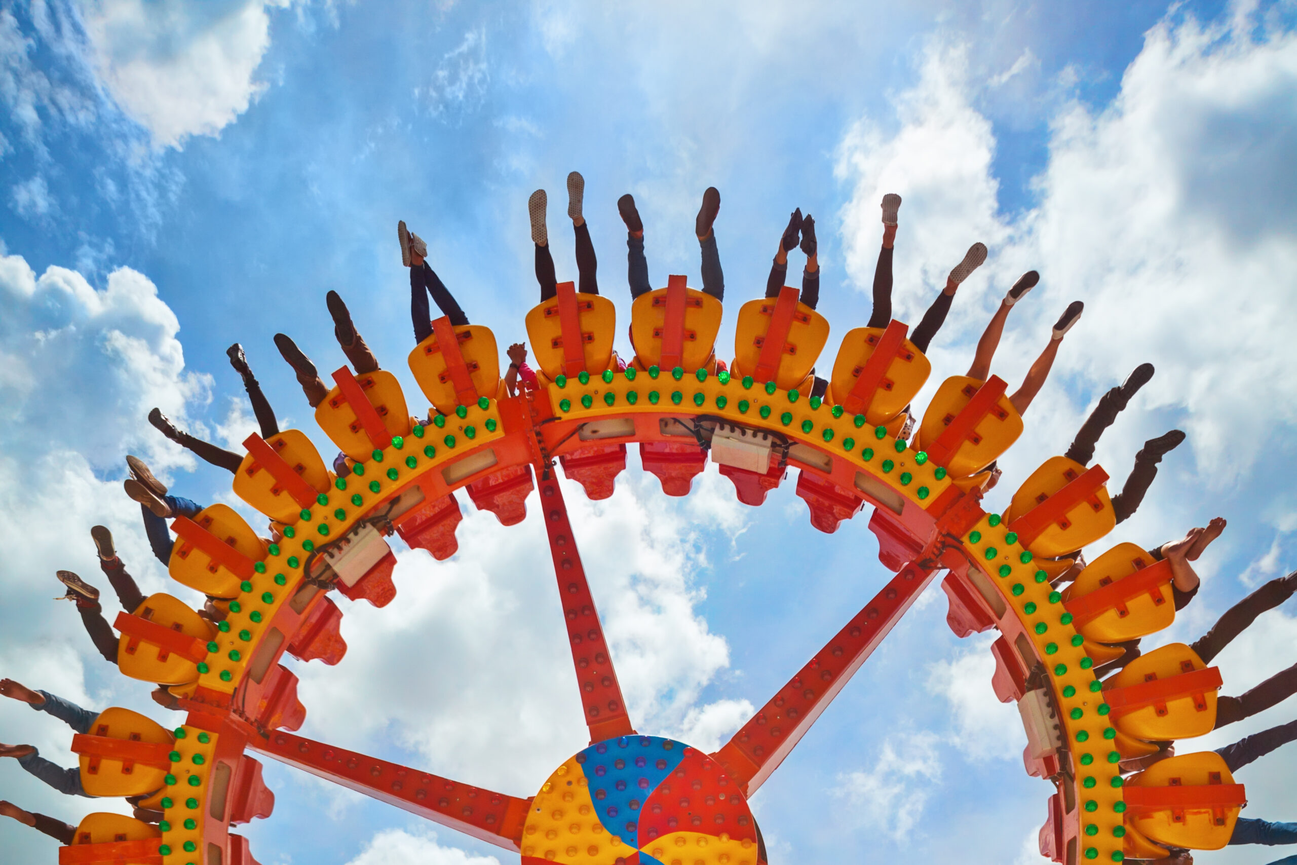 Funny photo of legs of women, men in amusement park riding with fun on extreme attraction swinging upside down high in air on sky background. Family lifestyle, people activity on holiday with children People on Cedar Point Amusement Ride