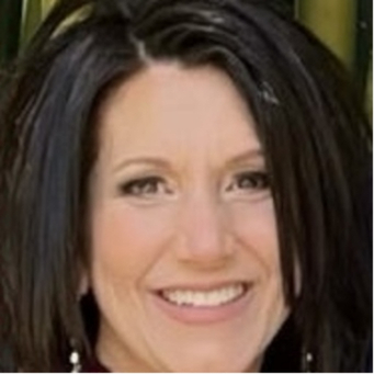 Professional headshot of a smiling woman with dark shoulder-length hair against a neutral background.