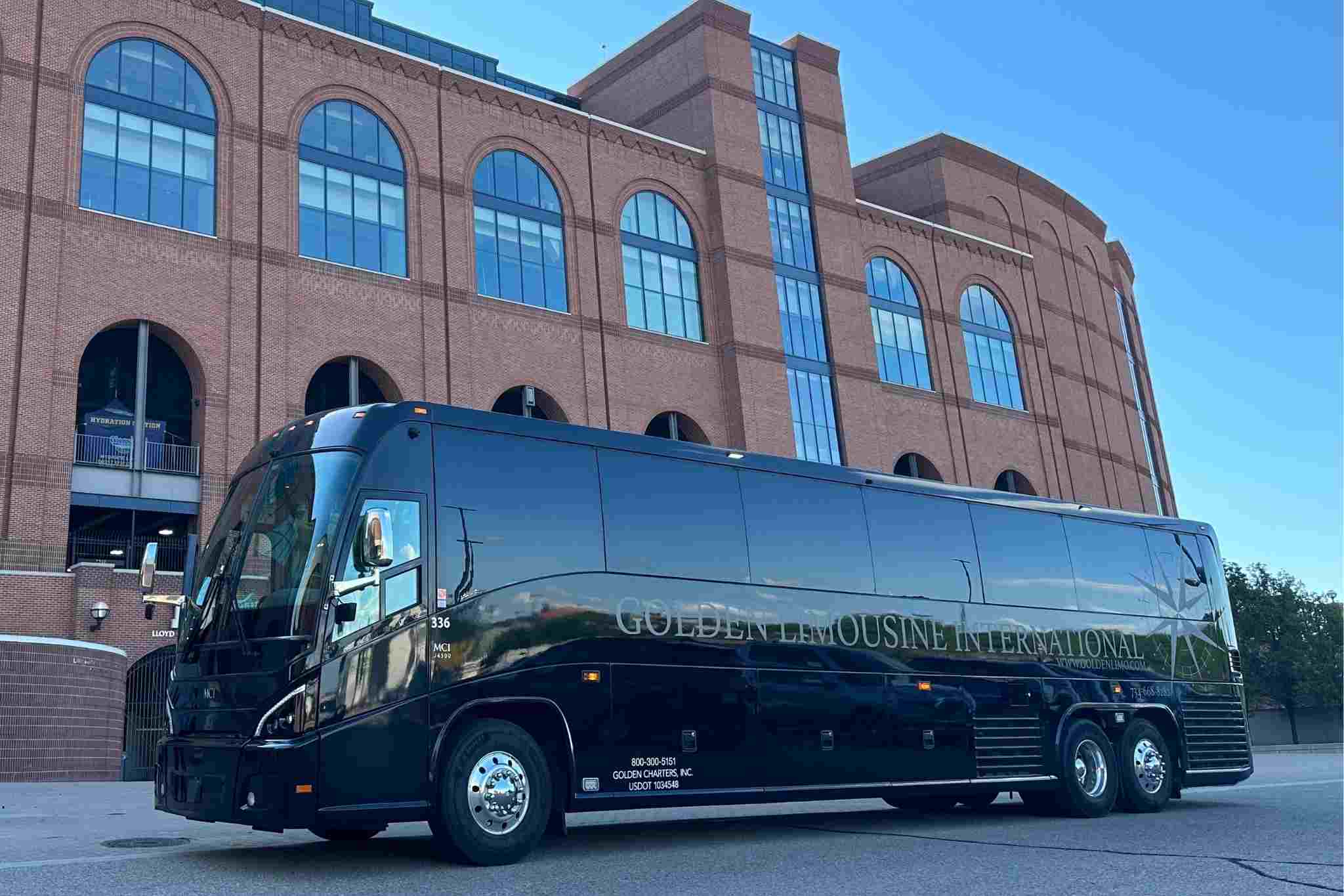 Black luxury motorcoach parked outside a basketball arena, providing group transportation for fans traveling to a major college basketball championship event.