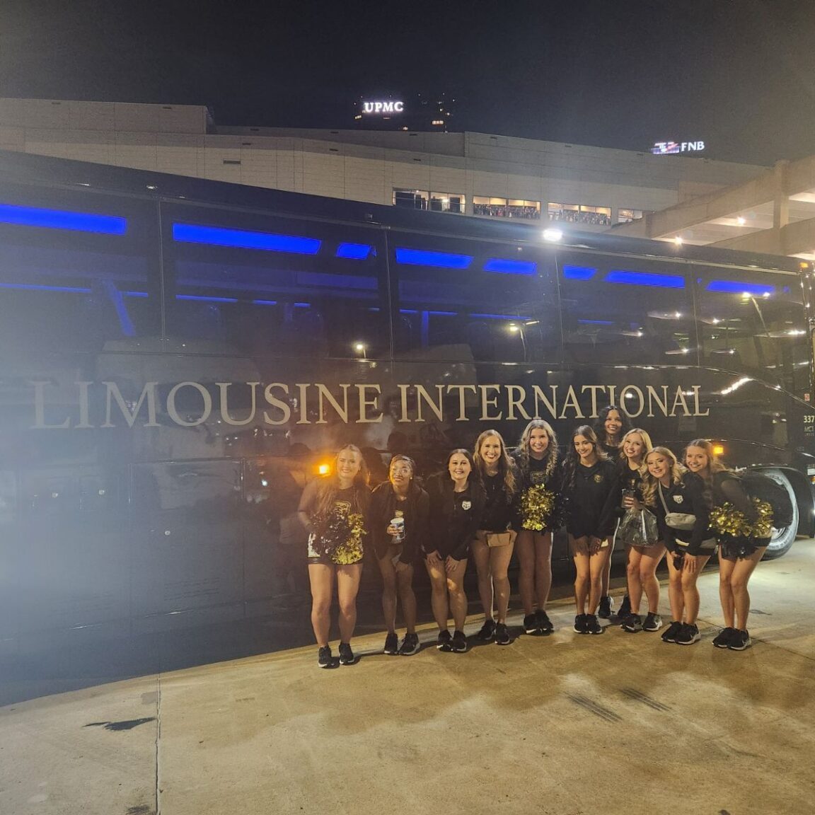 Oakland Cheering Squad in front of GLI Charter Bus